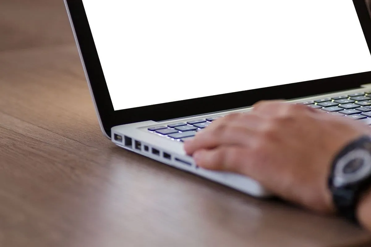 Close-up of hands typing on a laptop keyboard