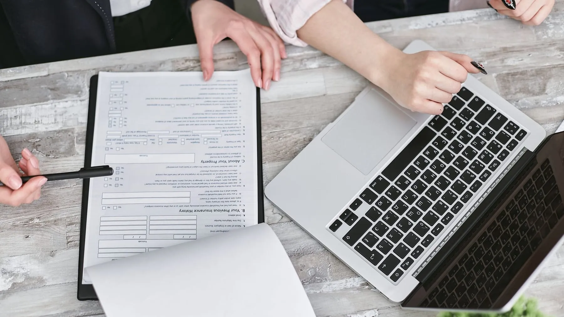 Two people reviewing business documents beside a laptop