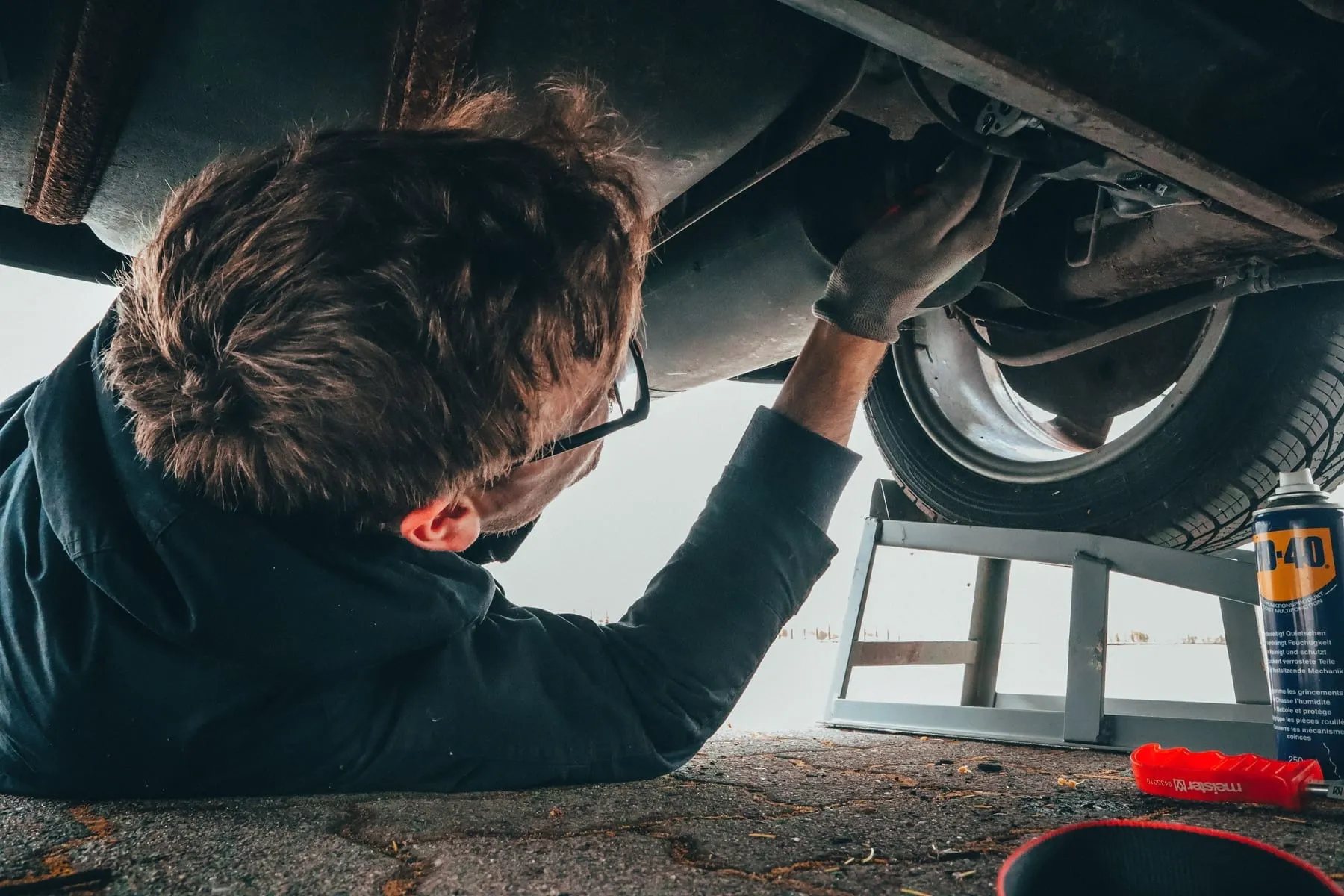 Mobile mechanic working on a car engine at a customer's driveway
